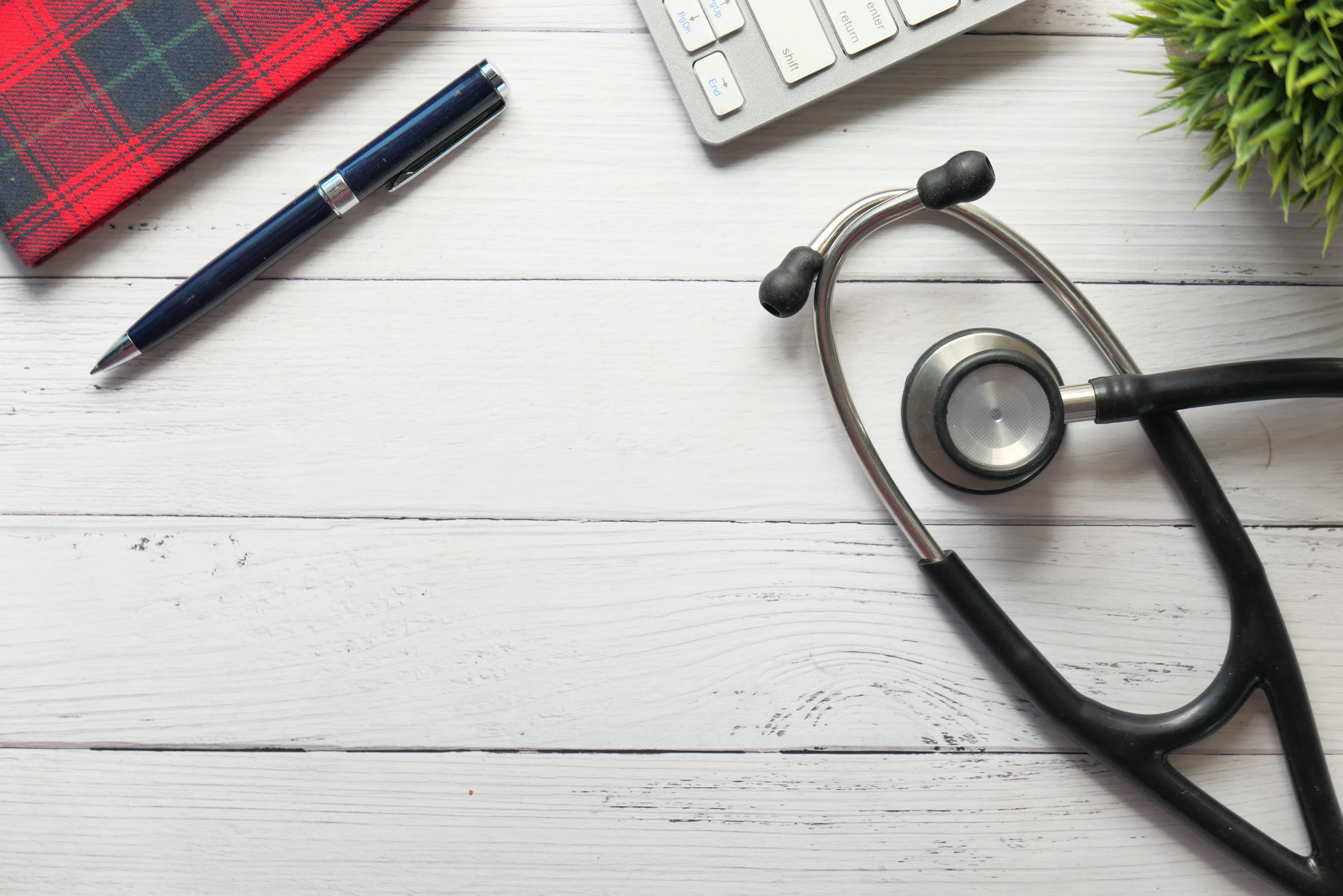 Doctors Workplace with Container, Keyboard and Notepad on Desk.